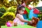 Baby toddler girl playing in outdoor tea party feeding her best friend Teddy Bear with candy