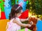 Baby toddler girl playing in outdoor tea party feeding her best friend Teddy Bear with candy gummy