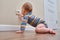 Baby toddler reaches into the electrical outlet on the home wall with his hand. Danger and protection of child fingers from