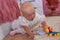 Baby with toys by the bed,in the parents` room by the bed a baby is playing, childhood memories