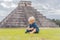 Baby traveler, tourists observing the old pyramid and temple of the castle of the Mayan architecture known as Chichen