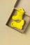 Baby yellow rubber boots in cardboard craft box on beige background. Waterproof polymeric footwear. Children`s shoes. Flat lay to