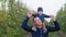 babyhood, little baby near caring father's neck while walking outdoors in an apple orchard