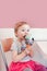 Babyl girl child with blue eyes eating licking ice cream in large waffle cone with colorful sprinkles