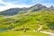 Bachalpsee, Switzerland - August 16, 2019: Cows grazing and walking among tourists by beautiful Bachalpsee lake in the Swiss Alps