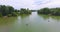 Back aerial flight over fisherman sitting in boat further pictorial landscape with forest and river with fishing boats