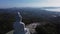 Back aerial view of huge Buddha statue located on the high mountain and looking at seaside