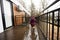 Back of baby girl walking on terrace of one-storey modular houses in spring rainy forest