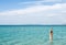 Back of beautiful woman wearing blue bikini standing in the water on Mediterranean sea coast, Cesme, Ilica beach, Turkey