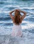 Back beautiful young woman floating in ocean or sea water, relaxing and taking care of herself. Fashion portrait of