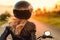 Back of blonde biker girl in a leather jacket and helmet on a motorcycle. Generative AI