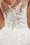 Back of the bride in a wedding dress. View of the back, beautiful openwork patterns, lace - decorated top dresses, waist, long zip