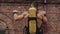 Back close view of muscular shirtless firefighter with oxygen tank on his back doing exercises on horizontal bar