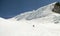 Back country skier skiing down a huge alpine glacier on a beautiful winter day with hanging ice seracs behind him