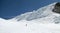 Back country skier skiing down a huge alpine glacier on a beautiful winter day with hanging ice seracs behind him