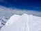 Back country skiers and mountain climbers near a high alpine summit cross with a narrow and exposed ridge leading towards them