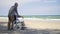 Back elderly woman disabled sitting in wheelchair and husband is a wheelchair user on the beach