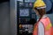 Back of factory worker woman with mask adjust button near the monitor of machine in workplace area. Concept of good management