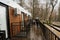 Back of father with daughters walking on terrace of one-storey modular houses in spring rainy forest