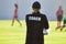 Back of female sport coach wearing COACH shirt at an outdoor sport field