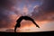 Back handspring of female gymnast in sunset sky