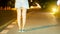 The back image of the girl standing at the side of the street at night and the orange