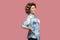 Back, kidney or spine pain. Profile side view portrait of sad young woman with curly hairstyle in casual blue shirt standing and