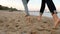 Back low angle view of romantic couple feet running on sand holding hands on beach near sea in slow motion. Boyfriend