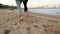 Back low angle view of romantic couple feet running on sand holding hands on beach near sea in slow motion. Boyfriend