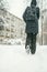 A back Low shot of a Beautiful youngwoman dressed in a black winter jacket with leather backpack walks in the snowy City