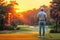 back of a male golfer with golf club standing on lawn on a golf course in summer at sunset