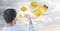 Back of man holding up glass device against cloudy sky with emojis and flare