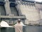 Back of a man looking at dam and turbines of a hydroelectric power station with falling water flows