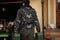 Back of man wear military jacket hold two canisters with gasoline against portable mobile backup standby generator