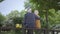 Back of old man sit in the bench in the park with bouquet of yellow flowers and hug woman with grey hair. Woman put her