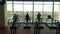 Back pan view of three sporty people, running on treadmills in a gym