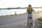 Back picture girl with yellow bicycle and river and road background at Sunset time