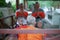 Back Portrait of old monk sits in front of group of people waiting for ordaining at the temple