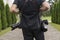 Back of professional wedding photographer in black shirt and with a two cameras an a shoulder straps against the green
