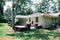 Back Rearview of exterior white cream brick 1950`s house with black shutters and a large lawn lot