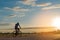 The back side of cyclist rides bicycle on sunset time background.