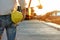 Back side of engineer holding yellow helmet and looking backhoe excavator transferring sand from barge into10-wheels trucks