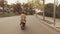 Back side of two young girls drive on scooter on road in city. Summer evening. Warm shades