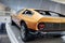 Back and side view of yellow retro sports coupe with left rear backlight, vertical doors, wide tires, chrome disc and
