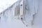 The back of the supermarket building has air conditioning on the wall covered with a thick layer of icicles