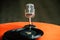 Back to 50s - nostalgic image of a 50`s microphone standing on an old orange table with old vinyl records
