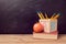 Back to school background with book, apple and pencils on wooden table