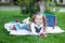 Back to school. Beautiful little schoolgirl with lunch, books and pencils lies on the grass against the background of the school.