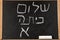 Back to School. Blackboard with Hello First Grade text in Hebrew written with white chalk.