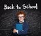 Back to school. Clever child in classroom on chalkboard background with science formulas